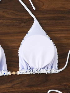 Detail of white lace bikini top with blue polka dot trim and gold metal chain rings