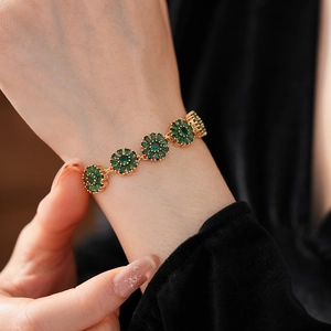 Macro shot of vintage gold flower bracelet with emerald zircon petals worn on wrist