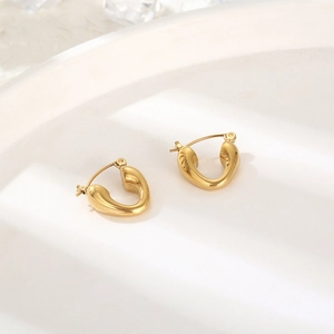 Close-up of golden U-shaped titanium steel earrings on a white ceramic display plate