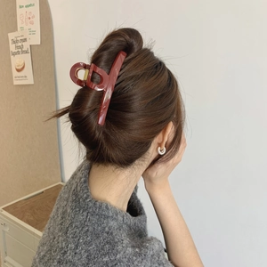Close-up of a large elegant dark red hair claw clip worn on a woman's hair