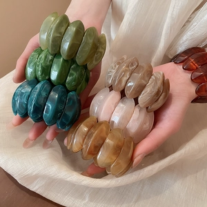Macro shot of colorful marble-textured acrylic resin oval bead elastic bracelets
