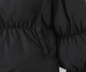 Detail shot of the side pocket and elastic hem on a black quilted puffer jacket