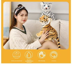 Close-up of soft orange and white stuffed tiger plushies held in a cozy home setting