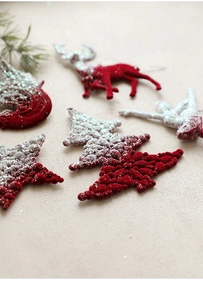 Detail of burgundy flocked Christmas ornaments with silver glitter in various shapes