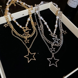 Detailed view of layered star pendant necklace with white pearls and a T-bar toggle clasp