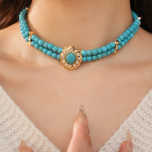 Gros plan d'un collier vintage en turquoise à double couche avec pendentif fleur dorée