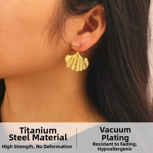 Détail des boucles d'oreilles feuille de ginkgo dorée en acier titane hypoallergénique