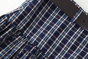 Nahaufnahme des blau karierten Midirocks mit braunem Gürtel aus hochwertigem Material
