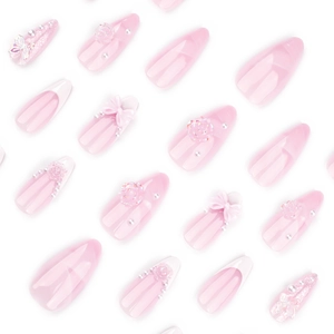 Pink French press-on nails with 3D bows, roses, and pearls in almond shape
