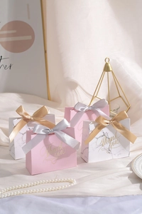 Detailed view of elegant pink and marble wedding gift boxes with gold satin ribbons