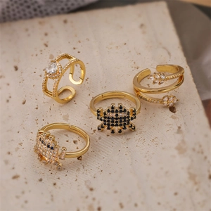 Detailed view of four gold-plated rings with zircon heart and leaf on stone background