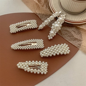 Detail of 5-piece cream pearl and silver alloy hair clip set on brown leather