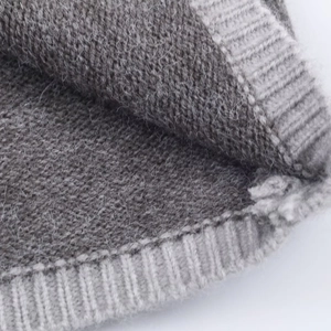 Gros plan d'un tissu gris en maille côtelée avec texture laineuse et coutures détaillées