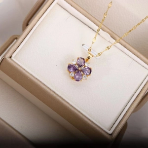 Élégant collier avec pendentif fleur violette et chaîne dorée dans un écrin à bijoux beige
