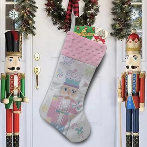 Detailed view of a Nutcracker Christmas stocking with pink cuff hanging on a festive door