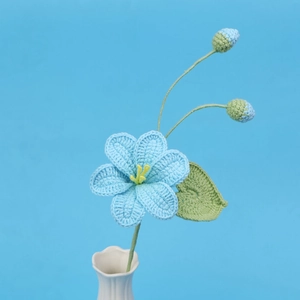Détail d'une fleur bleue au crochet dans un vase en céramique blanche sur fond bleu