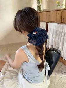 Detailed view of navy polka dot ruffle scrunchie with handmade heart label in a hairstyle
