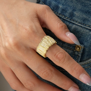 Macro shot of gold-plated wide band ring with dense vertical textured pattern on denim