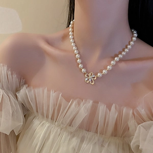 Elegante collana di perle barocche con pendente a fiore dorato indossata da una modella