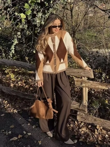 Outdoor street shot of a casual argyle knit cardigan paired with brown wide-leg trousers