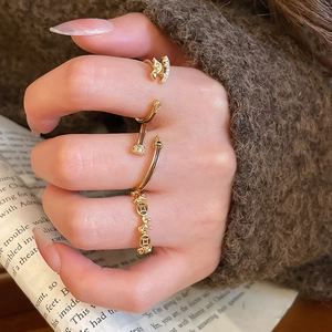 Close-up of gold-plated rings including geometric diamond-set and vintage coin styles