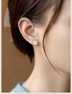 Detail view of a model wearing double-layered lotus pearl earrings with silver finish
