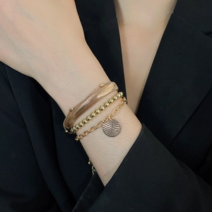 Dettaglio del set di quattro bracciali dorati con catena a serpente e ciondolo rotondo