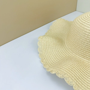 Detail of hand-woven straw sun hat showing intricate texture and scalloped fringe edges