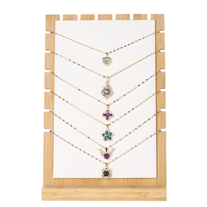 Bamboo necklace display stand with multiple colorful gemstone pendants on white velvet
