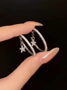 Detailed macro view of silver hoop earrings with sparkling zircon star charms