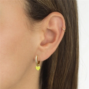 Macro detail of a crystal-encrusted gold earring with a bright yellow heart enamel pendant