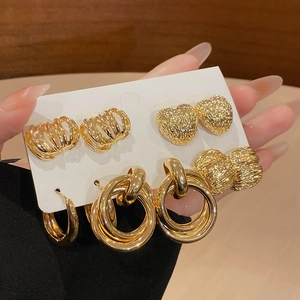 Detail of gold metal earring set featuring heart shapes and textured hoop earrings