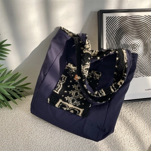 Detail of navy canvas tote bag featuring plush faux shearling pocket and leather label