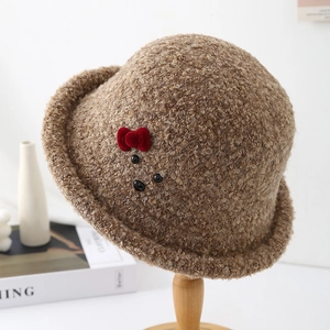 Detail of plush brown teddy wool bucket hat featuring a red velvet bow and animal face