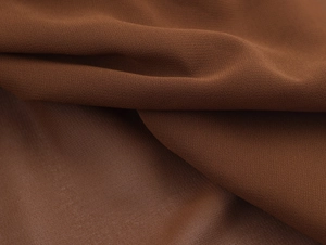 Détail macro du tissu mousseline marron foncé avec texture élégante et drapé doux