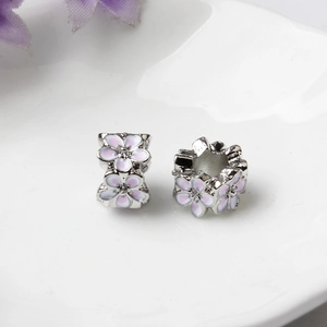 Macro shot of silver peach blossom charms with pink enamel and sparkling rhinestones
