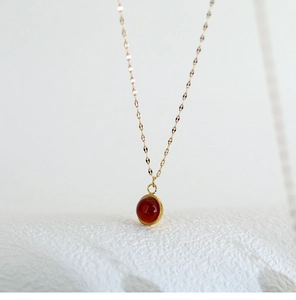 Detail shot of a round red agate pendant on an 18K gold-plated titanium necklace