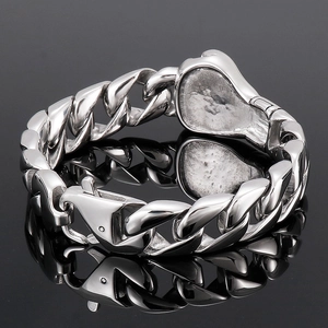 Macro shot of polished silver Cuban link bracelet with lobster clasp on black reflective surface