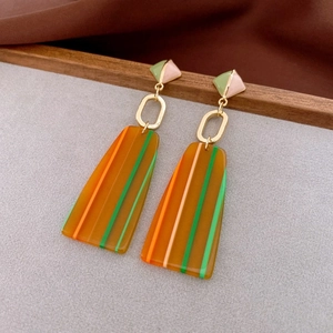 Macro shot of geometric amber resin drop earrings with stylish green and orange stripes