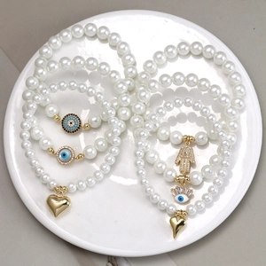 Detail of beaded evil eye bracelet set with pearl charms and Hand of Fatima pendants