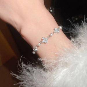 Detail of elegant silver clover pearl bracelet with zircon stones on female wrist