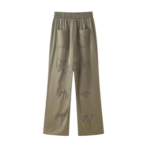 Detail of olive green satin wide-leg trousers with exquisite beaded embroidery on the cuffs