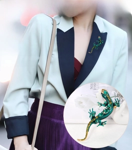 Détail d'une broche lézard avec cristaux verts et dorure sur une tenue de mannequin