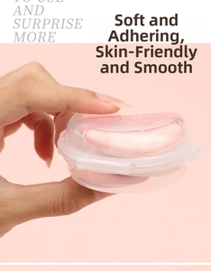 Macro shot of two soft peach-shaped finger puffs in a clear storage box for makeup