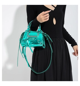 Close-up of metallic green patent leather handbag with silver rivets and buckle details