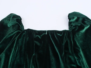 Detailed close-up of dark green velvet dress featuring a square neckline and hidden zipper