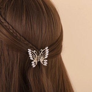 Elegant gold butterfly hair claw clip with white pearls on long brown hair