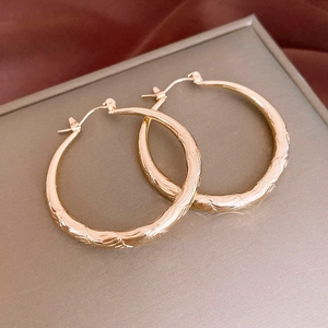 Detailed macro view of gold hoop earrings with intricate diamond pattern texture