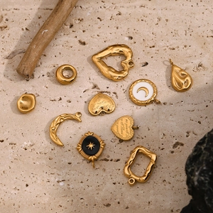 Detailansicht von goldenen Herz- und Mondanhängern auf minimalistischem Steinboden