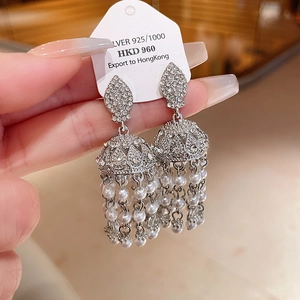 Detail of silver drop earrings with shimmering rhinestone inlay and pearl tassels
